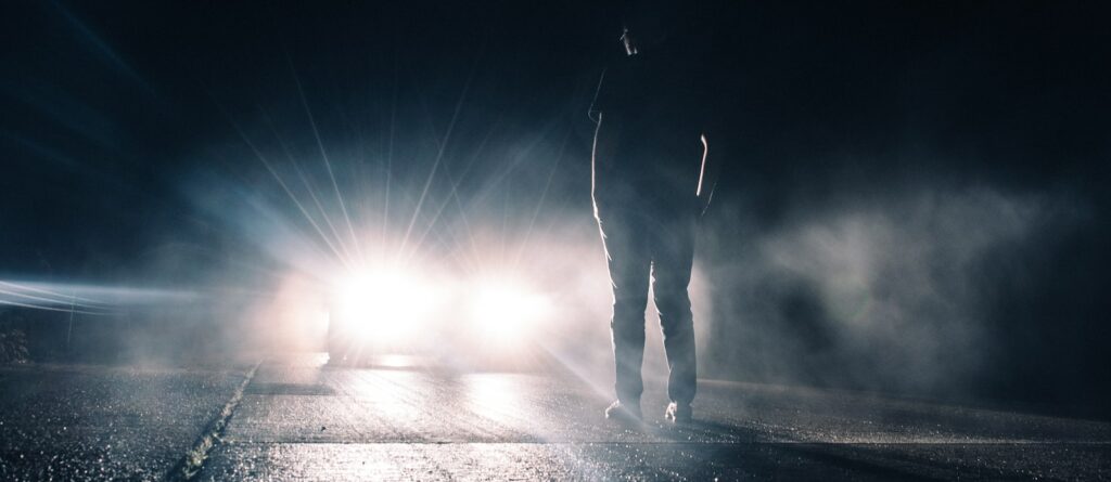 man standing in front of lighted car